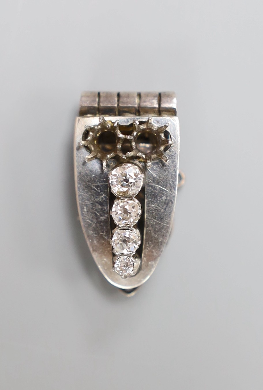 A white metal (stamped sterling silver) and graduated four stone diamond set clip brooch, 27mm, with two missing stones.
